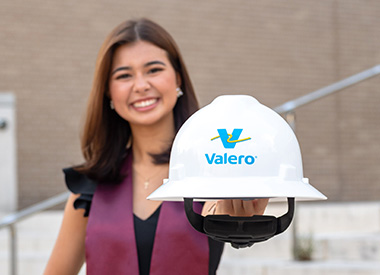 一个大学毕业生戴着valero hard Hat。